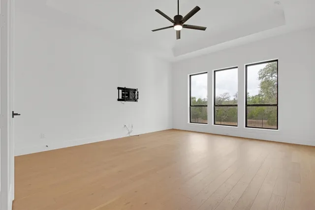 a view of an empty room with a window and wooden floor