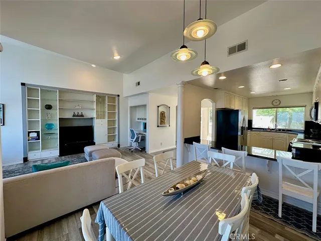 a kitchen with stainless steel appliances granite countertop a refrigerator a oven and white cabinets with wooden floors