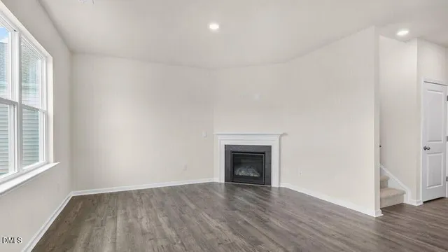 an empty room with wooden floor a fireplace and windows