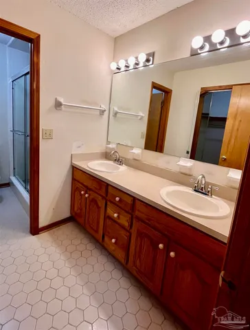 a spacious bathroom with a double vanity sink a large mirror and a shower