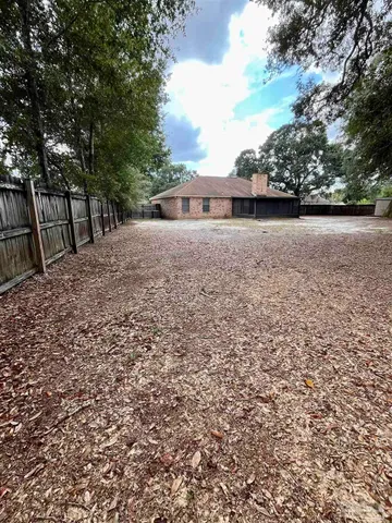 a backyard of a house with large trees and wooden fence