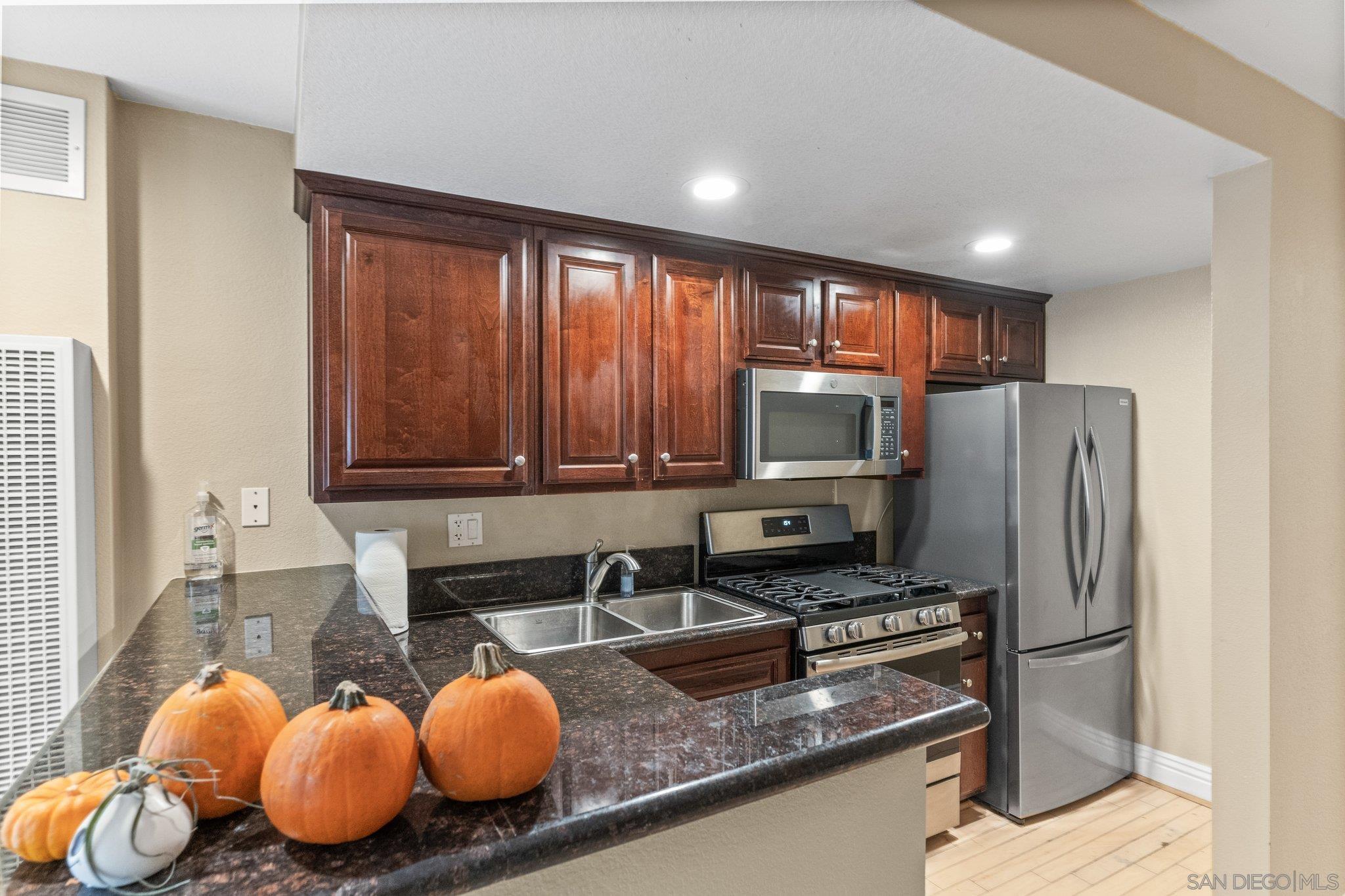 3927 Nobel Drive, Unit 67 San Diego, CA 92122 - Photo 1 of 28 a kitchen with granite countertop wooden cabinets a stove a oven a sink and a refrigerator