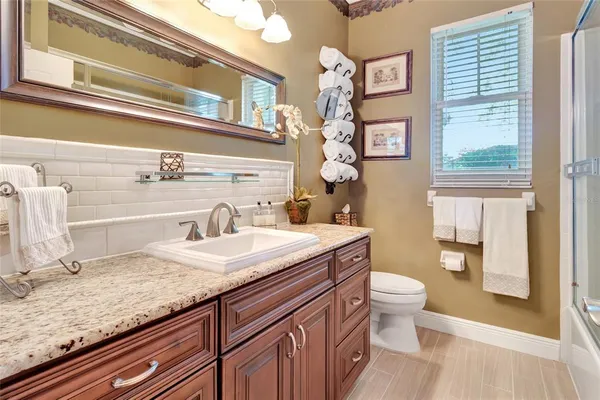 a bathroom with a granite countertop toilet sink and mirror