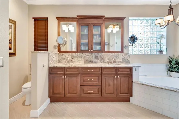 a bathroom with a granite countertop sink mirror and next to a window