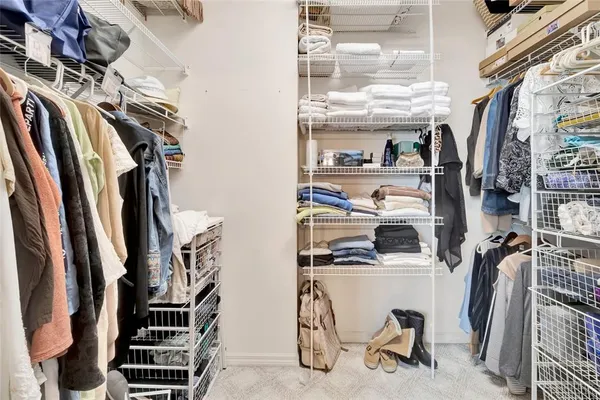 a view of walk in closet with clothes and shoes