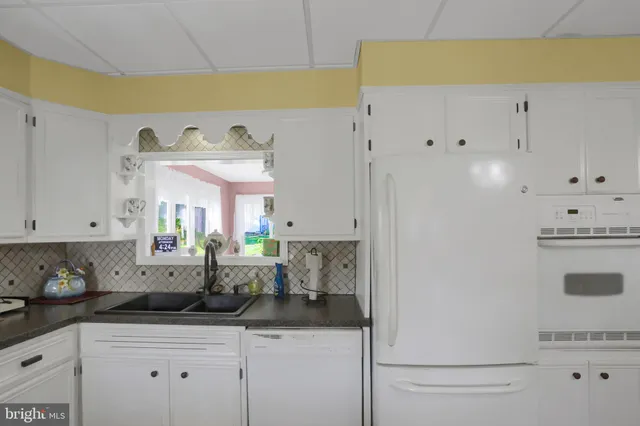 a kitchen with granite countertop white cabinets and white appliances