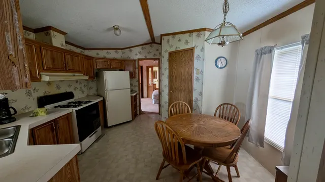 a kitchen with stainless steel appliances kitchen island granite countertop a table chairs and a refrigerator