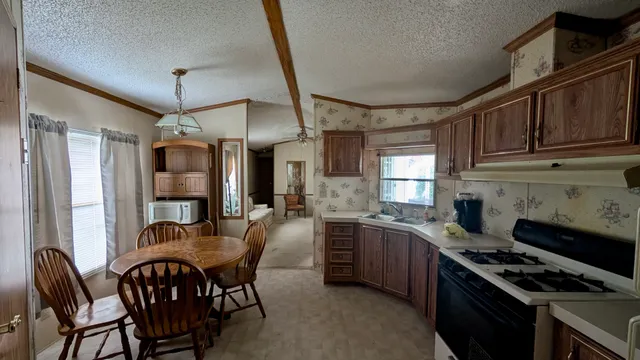 a kitchen with stainless steel appliances granite countertop a stove a sink dishwasher a dining table and chairs with wooden floor