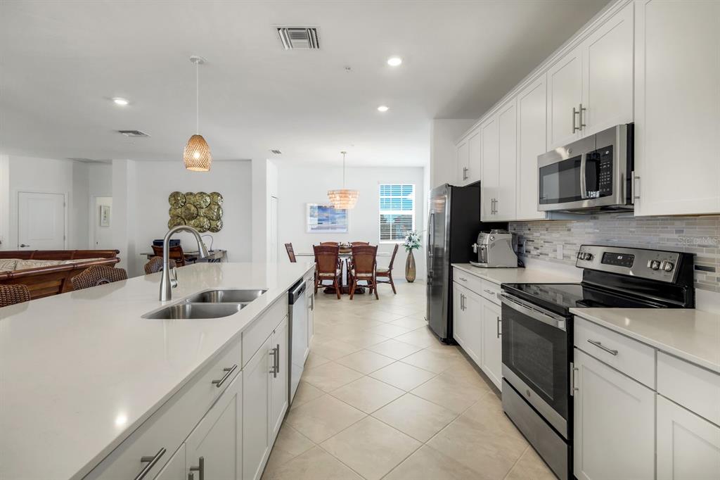 14180 Poppy Fld Loop Punta Gorda, FL 33955 - Photo 10 of 30 a kitchen with stainless steel appliances a sink a stove top oven a chimney a dining table and chairs