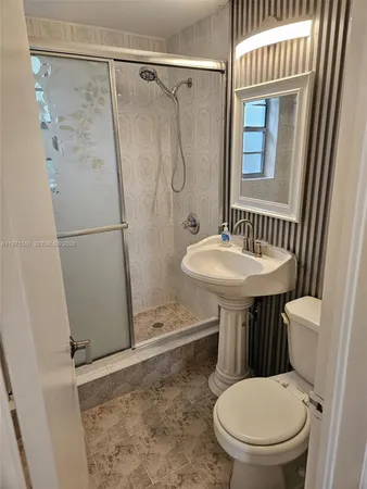 a bathroom with a sink a toilet a mirror and shower