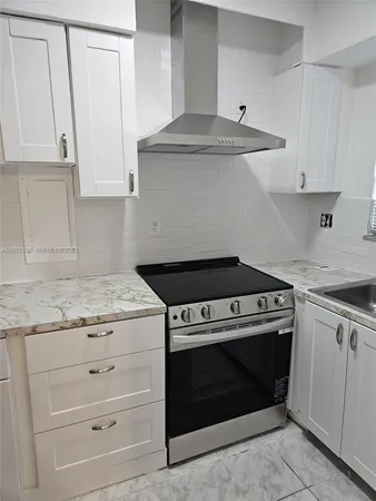 a kitchen with granite countertop white cabinets and a stove