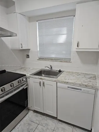 a view of cabinets a sink and a stove in a kitchen
