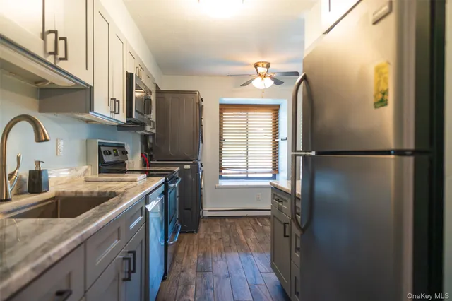 a kitchen with stainless steel appliances granite countertop a refrigerator a sink dishwasher a stove and a dining table with wooden floor