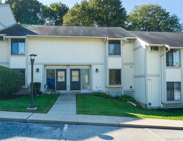 a view of a house with a yard plants and large tree