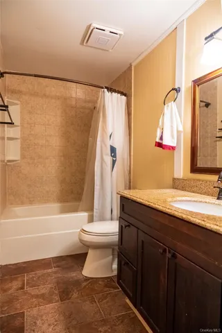 a bathroom with a granite countertop bathtub shower sink vanity and toilet