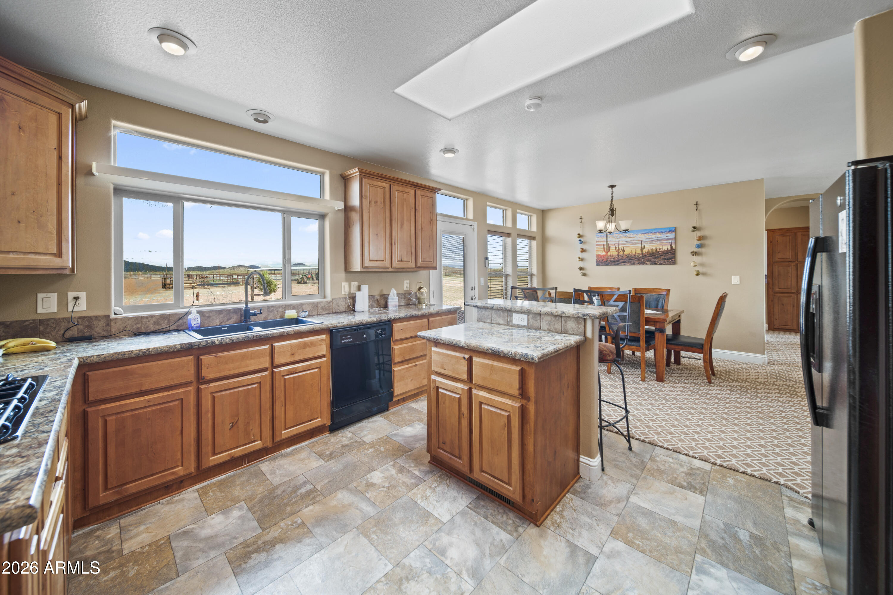 46109 West J-1 Ranch Road Wickenburg, AZ 85390 - Photo 17 of 32 a kitchen with stainless steel appliances granite countertop a stove top oven a sink a dining table and chairs