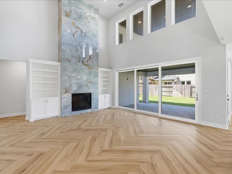 4710 Pecos Ridge Lane Sugar Land, TX 77479 - Photo 24 of 49 This spacious living room features a stunning floor-to-ceiling marble fireplace, built-in shelving, and elegant herringbone wood floors. Large windows and sliding doors provide ample natural light and a view of the backyard.
