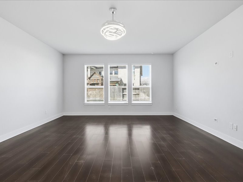 4710 Pecos Ridge Lane Sugar Land, TX 77479 - Photo 33 of 49 This spacious room features sleek dark hardwood floors, a modern ceiling light, and ample natural light from three large windows with a pleasant view.