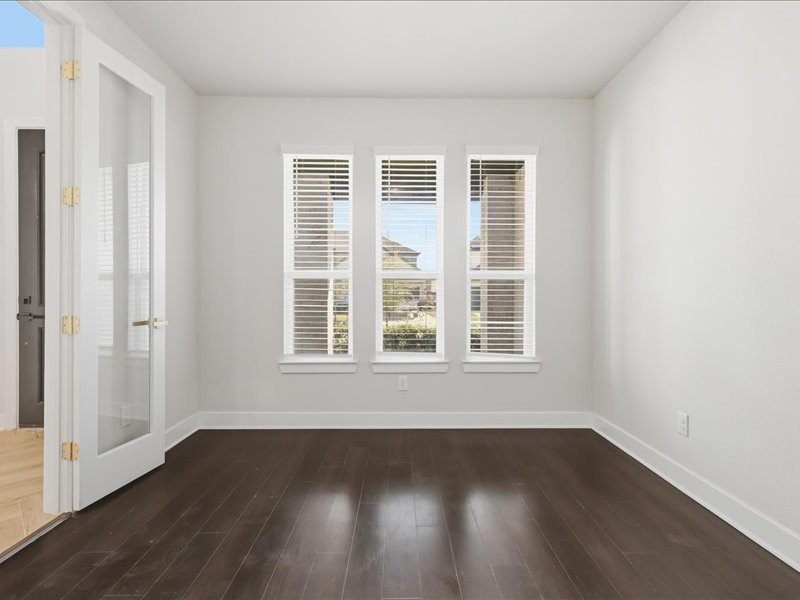 4710 Pecos Ridge Lane Sugar Land, TX 77479 - Photo 35 of 49 This room features dark hardwood floors and ample natural light from three large windows with blinds. A set of glass French doors adds elegance and versatility, making it ideal for an office or cozy sitting area.