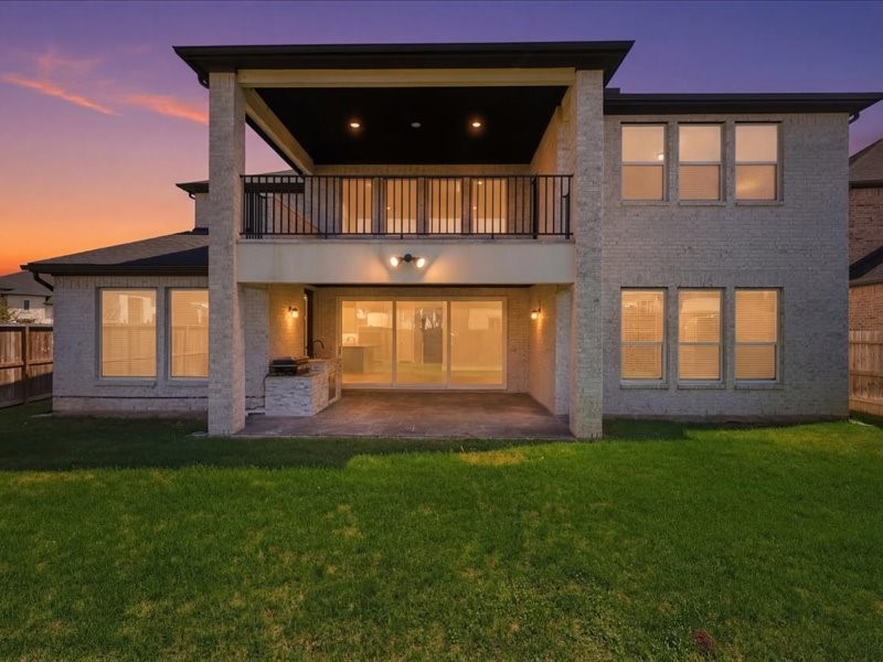 4710 Pecos Ridge Lane Sugar Land, TX 77479 - Photo 4 of 49 This photo showcases a modern two-story home featuring a spacious backyard with a covered patio and balcony. Large windows and sliding doors allow ample natural light, creating a welcoming atmosphere perfect for entertaining.