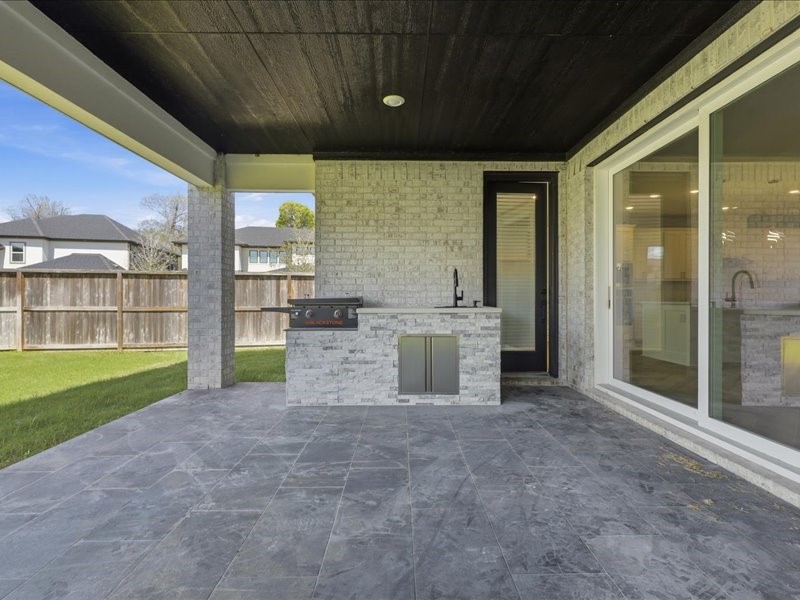4710 Pecos Ridge Lane Sugar Land, TX 77479 - Photo 41 of 49 This outdoor patio features a covered space with sleek tile flooring, a built-in grill and sink, and large sliding glass doors connecting to the interior, perfect for entertaining.