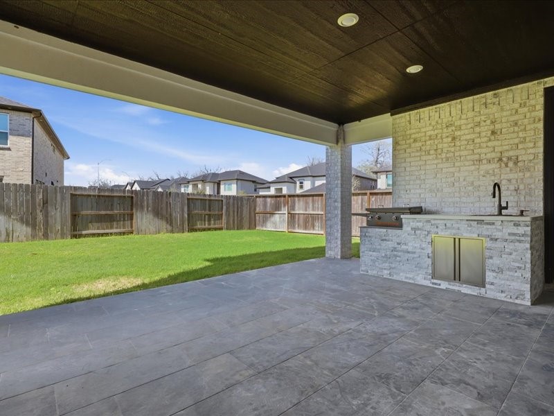 4710 Pecos Ridge Lane Sugar Land, TX 77479 - Photo 43 of 49 Spacious covered patio with a tiled floor, built-in outdoor kitchen, and a view of a fenced backyard, perfect for entertaining and relaxation.