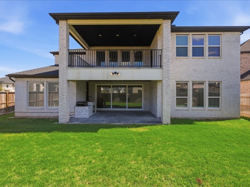 4710 Pecos Ridge Lane Sugar Land, TX 77479 - Photo 45 of 49 Spacious two-story home exterior with a large covered patio, balcony, and lush green lawn, perfect for outdoor entertaining.