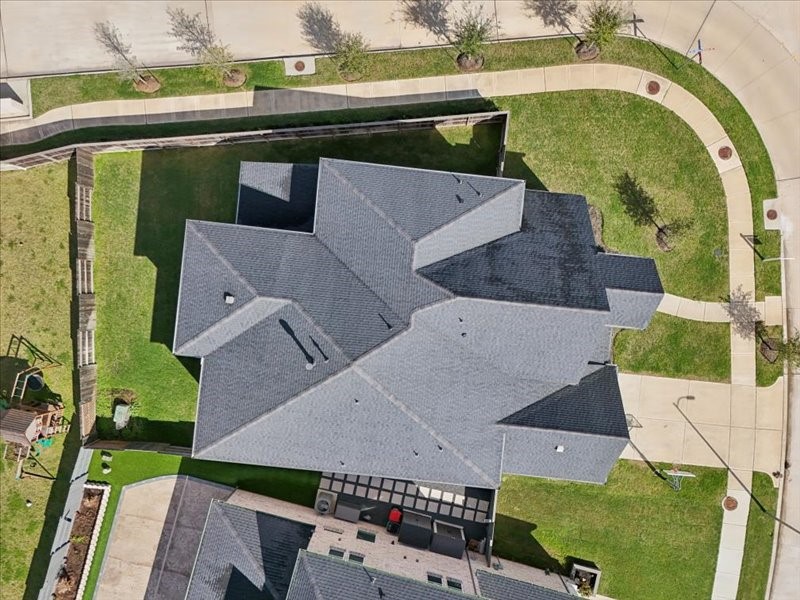4710 Pecos Ridge Lane Sugar Land, TX 77479 - Photo 48 of 49 This aerial view showcases a spacious home with a complex roof design, situated on a corner lot. The property features a well-maintained lawn, a fenced backyard, and nearby sidewalks, offering both privacy and accessibility.