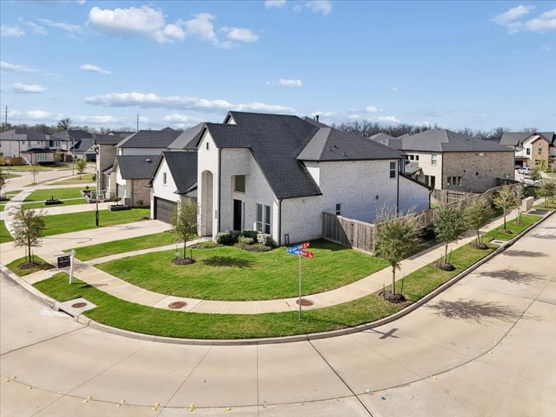4710 Pecos Ridge Lane Sugar Land, TX 77479 - Photo 49 of 49 This photo shows a modern, two-story corner house with a spacious yard, situated in a well-maintained suburban neighborhood. The exterior features white brick and a dark roof, with a fenced backyard and a two-car garage. The area appears quiet with tree-lined streets.