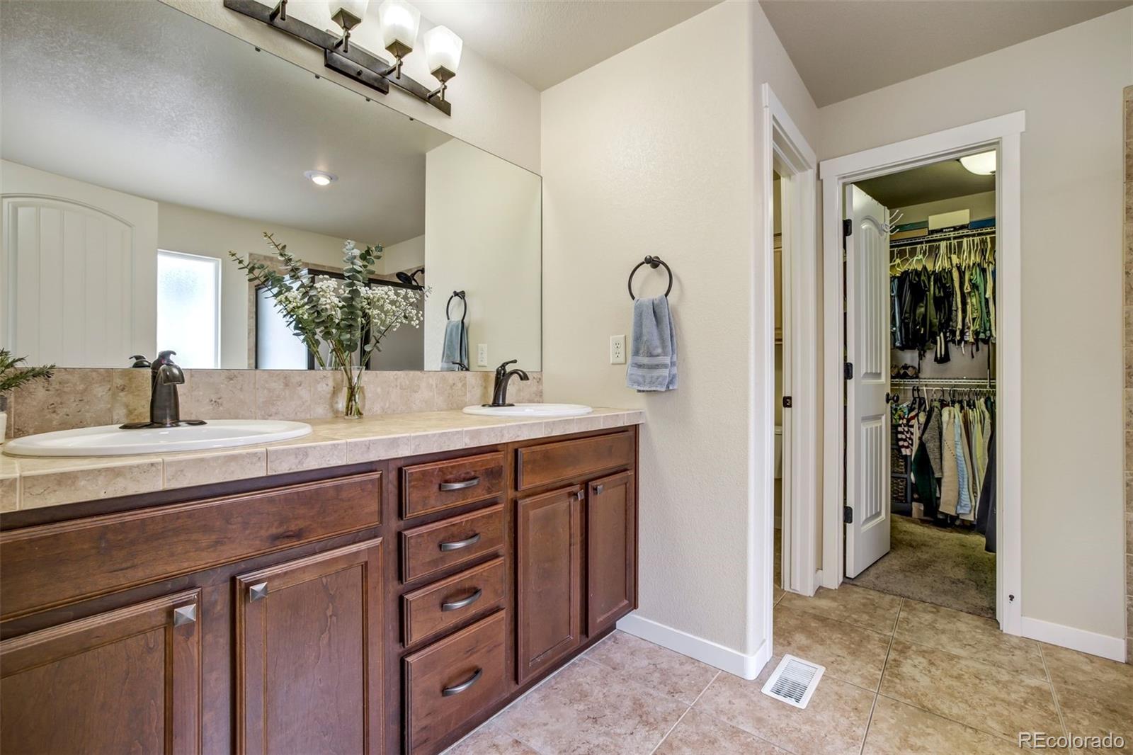 4970 Rabbit Mountain Court Colorado Springs, CO 80924 - Photo 18 of 50 a spacious bathroom with a double vanity sink a mirror and shower