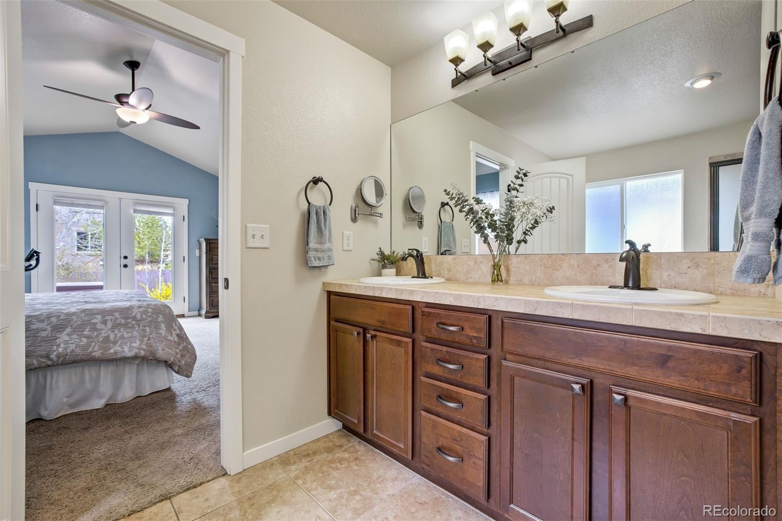 4970 Rabbit Mountain Court Colorado Springs, CO 80924 - Photo 19 of 50 a spacious bathroom with a granite countertop sink a mirror and a vanity