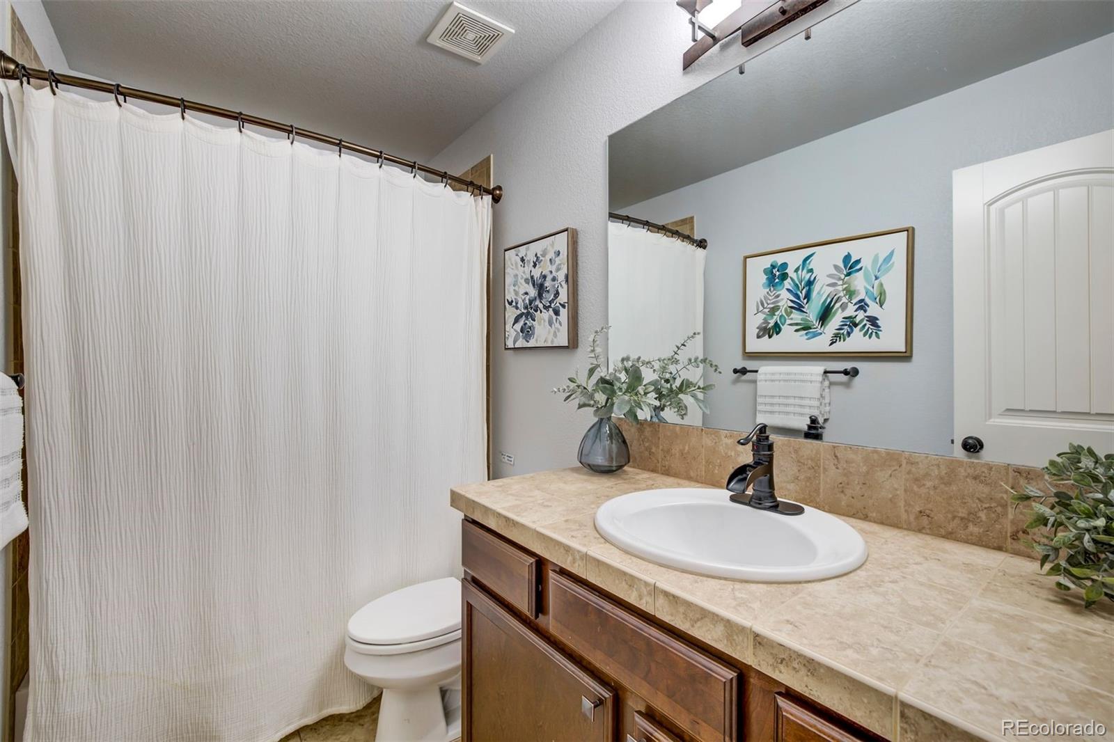 4970 Rabbit Mountain Court Colorado Springs, CO 80924 - Photo 24 of 50 a bathroom with a granite countertop sink and a mirror with toilet