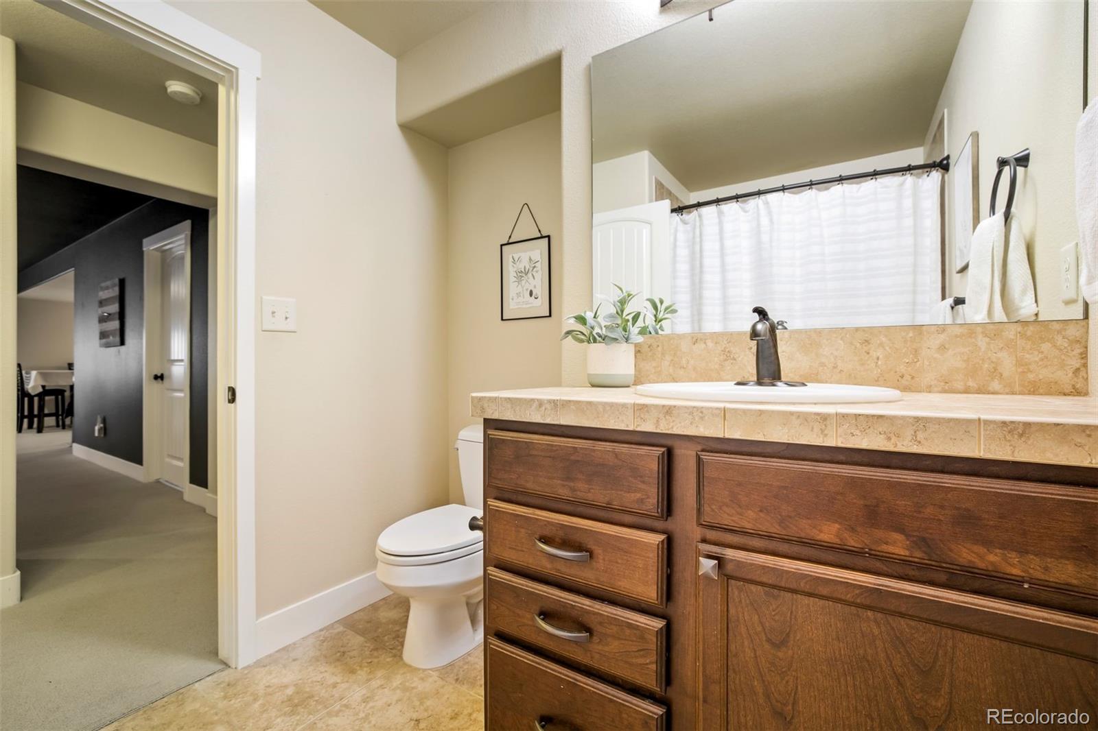 4970 Rabbit Mountain Court Colorado Springs, CO 80924 - Photo 39 of 50 a bathroom with a granite countertop sink a toilet and a mirror