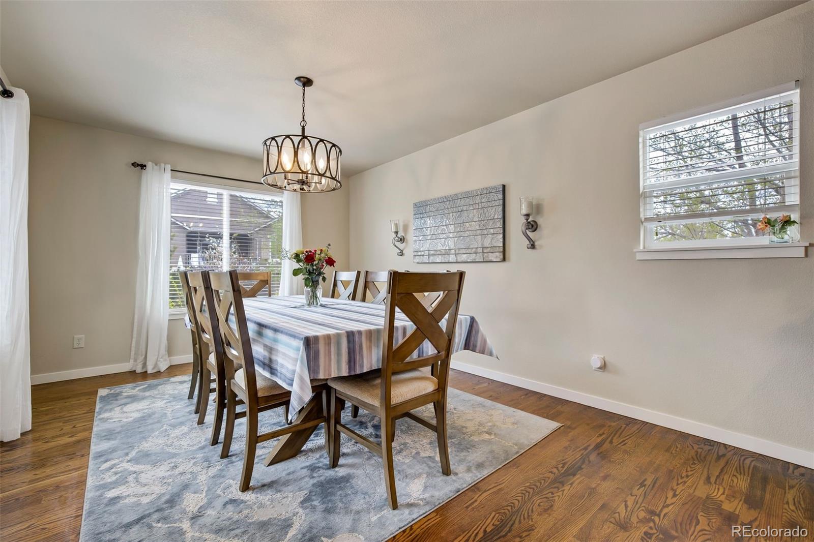 4970 Rabbit Mountain Court Colorado Springs, CO 80924 - Photo 7 of 50 a dining room with wooden floor a chandelier a wooden table and chairs