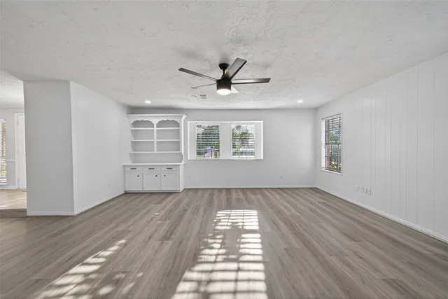 a view of an empty room with window and wooden floor