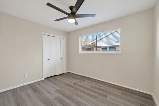 an empty room with wooden floor and ceiling fan