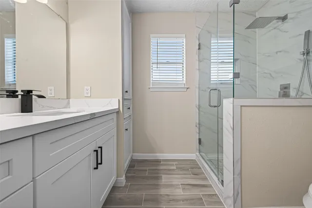 a view of an empty room with wooden floor and a ceiling fan
