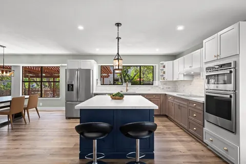 a kitchen with stainless steel appliances granite countertop a stove a sink dishwasher a dining table and chairs with wooden floor