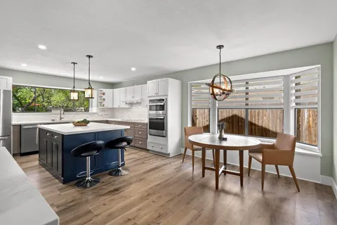 a kitchen with stainless steel appliances granite countertop a kitchen island hardwood floor a dining table and chairs