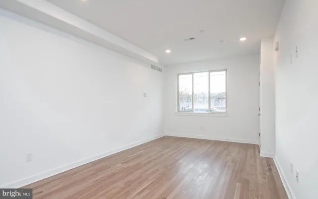 an empty room with wooden floor and windows