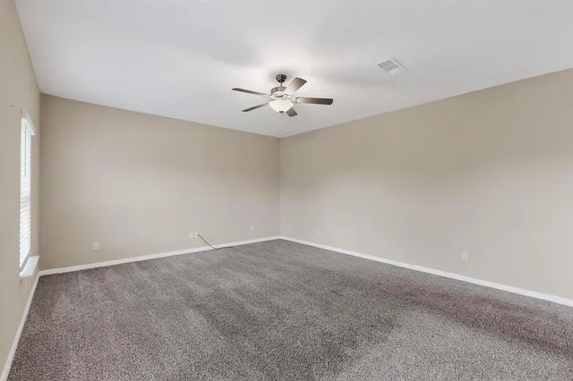 a view of an empty room with a ceiling fan and window