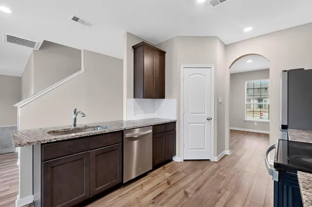 a kitchen with granite countertop a sink cabinets and wooden floor