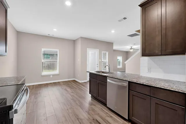 a kitchen with stainless steel appliances granite countertop a sink a stove and a wooden floors