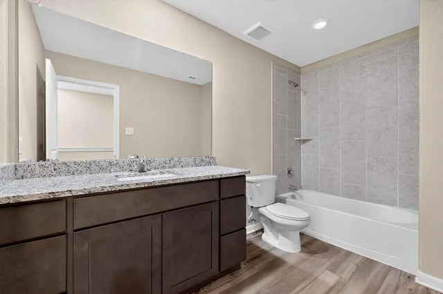 a bathroom with a granite countertop toilet a sink and a mirror