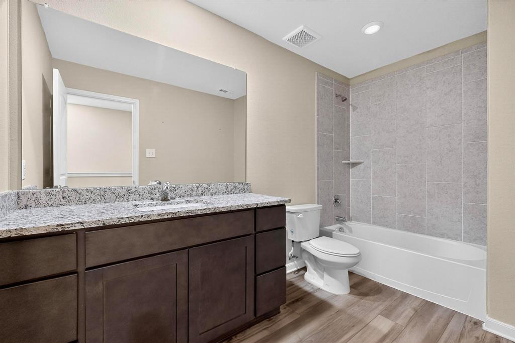 305 Honeysuckle Lane Princeton, TX 75407 - Photo 18 of 39 a bathroom with a granite countertop toilet a sink and a mirror