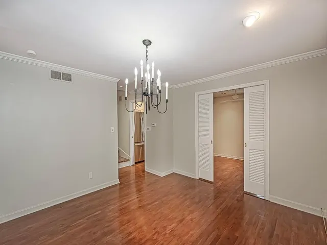 a view of a room with wooden floor chandelier and closet