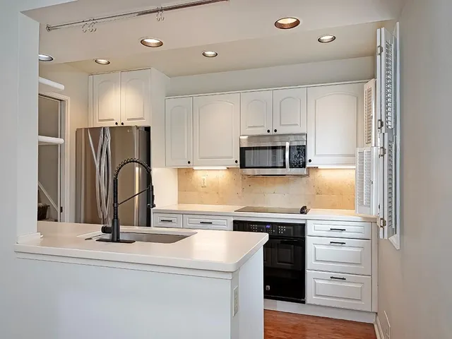 a kitchen with a sink stainless steel appliances and white cabinets