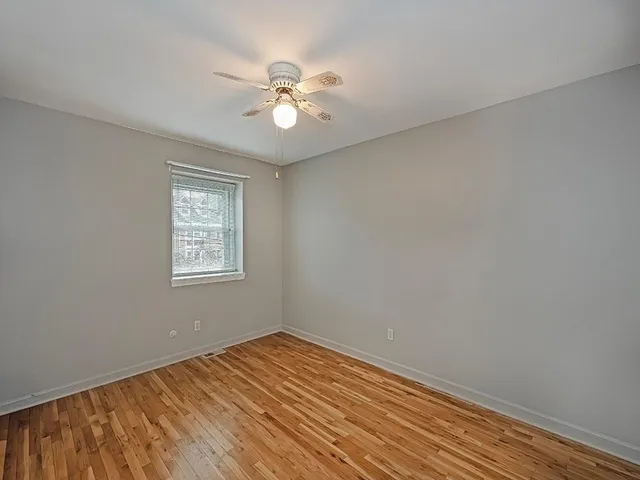 a view of a room with wooden floor and a chandelier fan