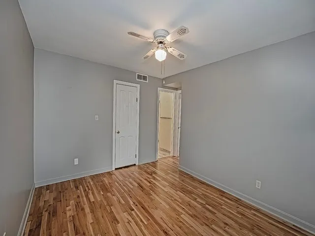 a view of a room with wooden floor and a ceiling fan
