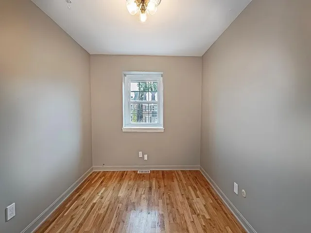an empty room with a window and wooden floor